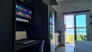 Habitación de hotel moderna con escritorio, silla y ventana grande que ofrece vistas al exterior.