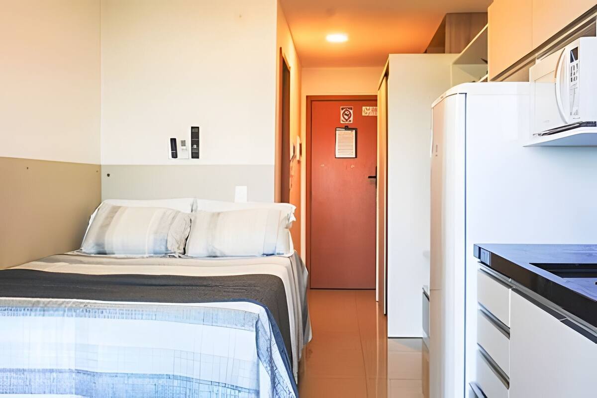 Ett hotellrum med en säng, ett skrivbord och ett kylskåp.