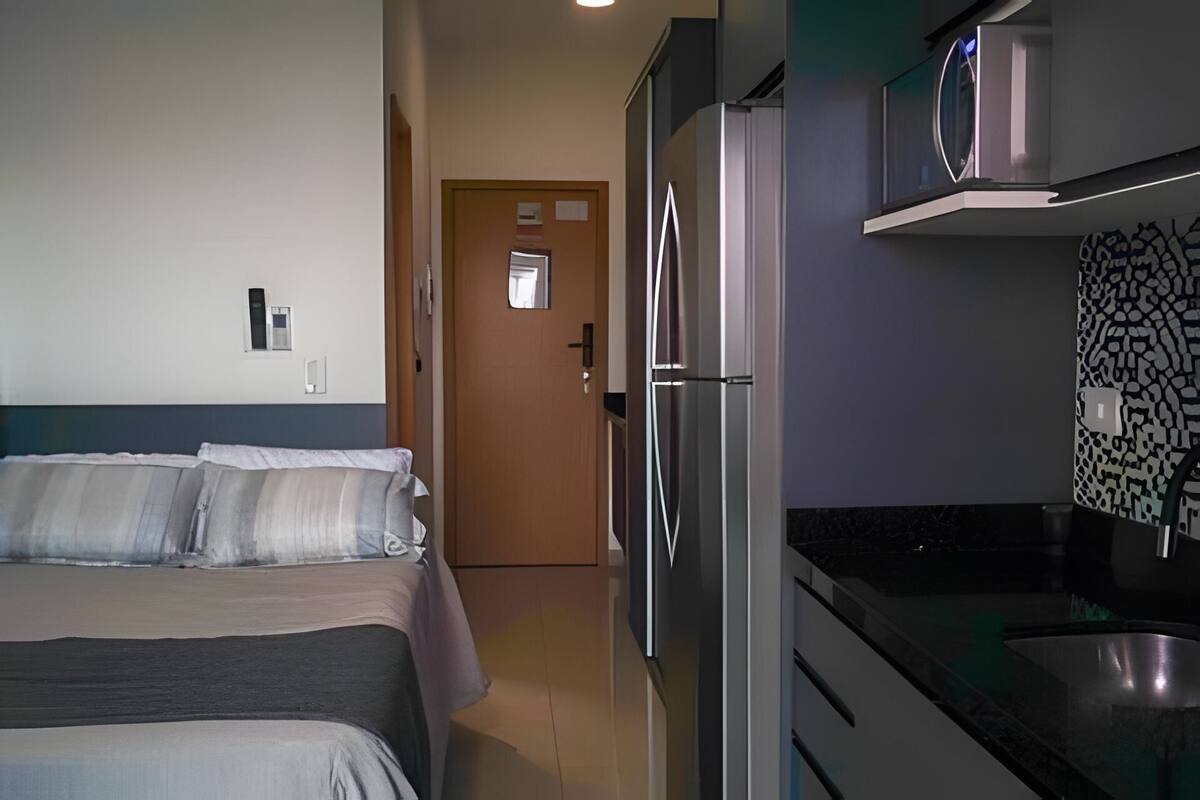 Ett hotellrum med en säng, ett kylskåp, en mikrovågsugn och ett handfat.