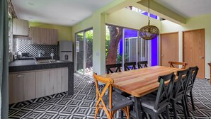 A modern kitchen with a dining area, featuring a large wooden table and chairs, a patterned floor, and a view of greenery outside. - Escape to the countryside: Private House in Boutique Complex. (Tepoztlán)