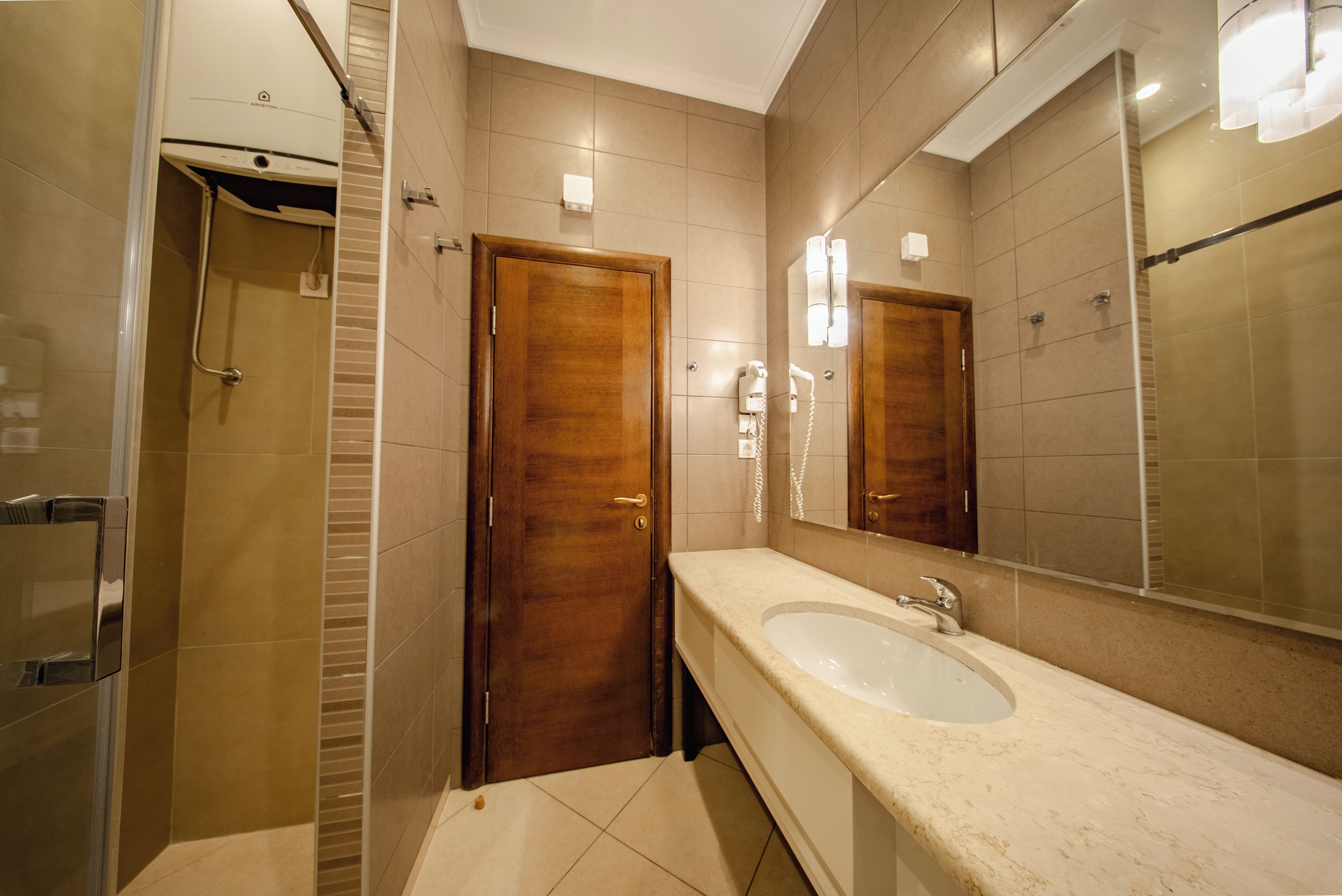 A modern bathroom with a large mirror, a sink, and a shower.
