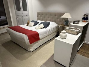 A neatly arranged bedroom with a bed, bedside table, lamp, and decorative items.