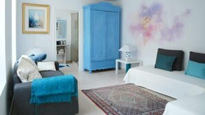 A modern bedroom with a bed, a sofa, a blue wardrobe, and a small table with a lamp.