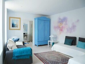 Une chambre à coucher moderne avec un lit, un canapé, une armoire bleue et une petite table avec une lampe.