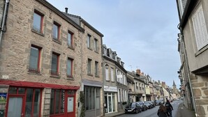 A street with buildings, a café, and parked cars.