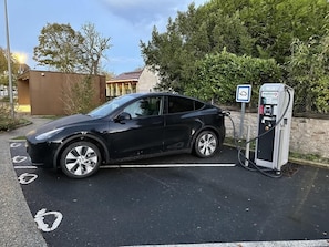 A black car parked at a charging station with a sign indicating it is a public charging point. - Modern Loft with Play Area in Dun-le-Palestel (Dun-le-Palestel)