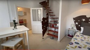 A bedroom with a bed, a nightstand, a dresser, and a staircase with a star-patterned railing.
