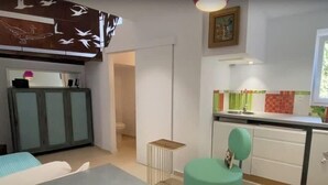 A compact living space with a kitchenette, a dining area, and a bedroom.