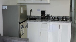 Een moderne keuken met witte kastjes, een roestvrijstalen koelkast, een koffiezetapparaat en een gasfornuis.