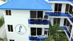 Um hotel com telhado azul, várias varandas e área de piscina com espreguiçadeiras.
