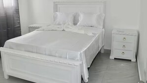 Ein helles Schlafzimmer mit Bett, Nachttischen und einer Kommode.