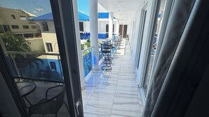 Un corridoio con una porta in vetro che dà su un balcone con posti a sedere all'aperto e vista sulla piscina.