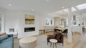 Ein modernes Wohnzimmer mit Kamin, Essbereich und Küche.