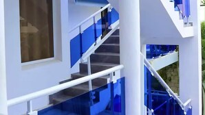 Un bâtiment moderne doté d’un escalier, de rampes en verre et d’une grande fenêtre.