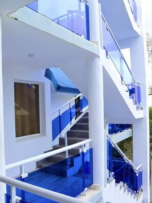 Un bâtiment moderne doté d’un escalier, de rampes en verre et d’une grande fenêtre.