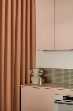 A kitchen with a pink cabinet, a white appliance, and a green tiled backsplash. - Stylish Balcony Apartment | King Bed | Central Krakow (Kraków)