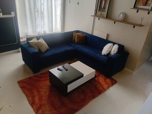 Un saló amb un sofà seccional blau, una taula de cafè negra i una catifa vermella.