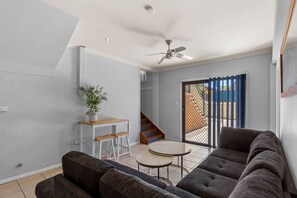 A modern living room with a sofa, a small table, and a potted plant. - Forster 8BR home, free parking, near shop & beach (Forster)