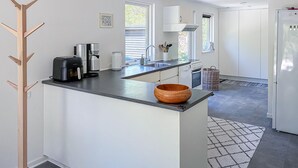 Eine moderne Küche mit Kochinsel, eingebauten Geräten und Blick zum Essbereich.