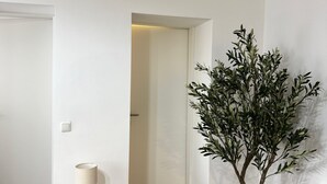 A room with a toilet, a potted plant, and a door leading to another room.