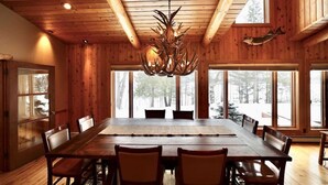 Een houten interieur met een grote eettafel, stoelen en een kroonluchter.