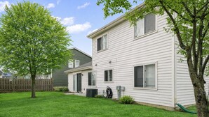 A two-story residential building with a well-maintained lawn and a wooden fence. - Lovely 3BR Crystal Lake home Nearby park and Lake! (Crystal Lake)