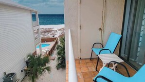 A balcony with a pool, chairs, and a door.