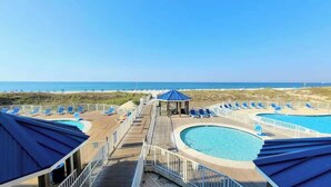 A pool area with multiple swimming pools, lounge chairs, and a gazebo.