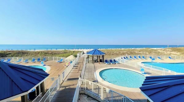 A pool area with multiple swimming pools, lounge chairs, and a gazebo. - Snowbird Rate Beachfront Complex Studio Sleeps 2! (Orange Beach)