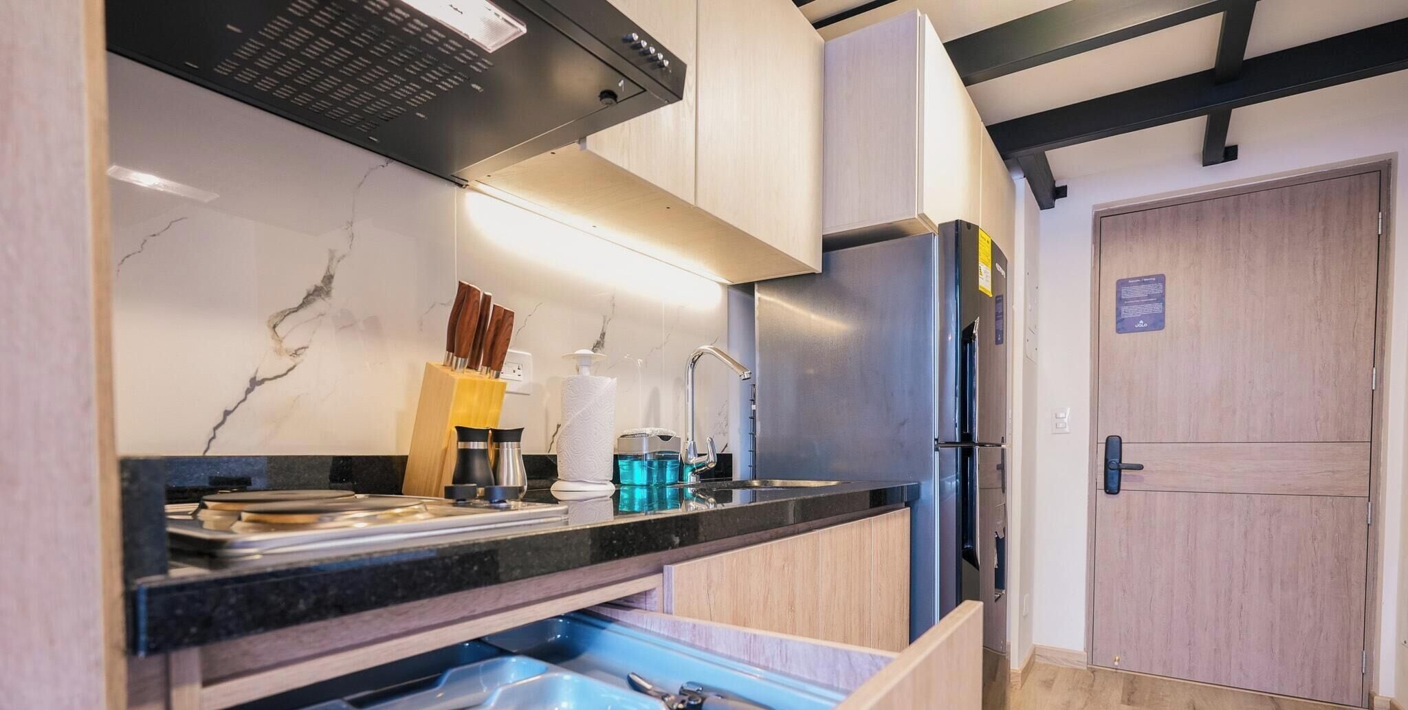 A compact kitchen with a built-in oven, a sink, and a wooden cabinet.