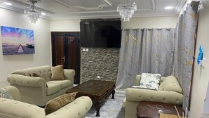 A living room with two sofas, a coffee table, a TV stand, and a chandelier. - 8 Bdrm luxury at Secluded Estate with Free 24/7 Solar. No more electricity cost (Freetown)