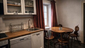 Uma cozinha compacta com pia, lava-louças e um espaço de refeições com mesa de madeira redonda e cadeiras.