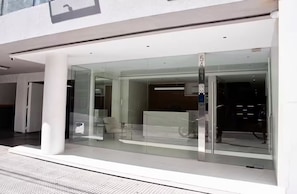 Ein moderner Hotel Eingangsbereich mit Glasfassade, einer Rezeption und einem sichtbaren Aufzug.