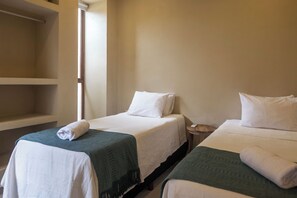 Two single beds with white linens and green blankets, a wooden nightstand, and a white wardrobe. - Casa Taormina: 10 guests • Air Conditioning • Safe Neighborhood • La Punta • Starlink (La Barra de Colotepec)