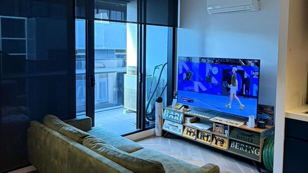 Una sala de estar moderna con un sofá verde, un televisor y un piso con estampado de espiga.