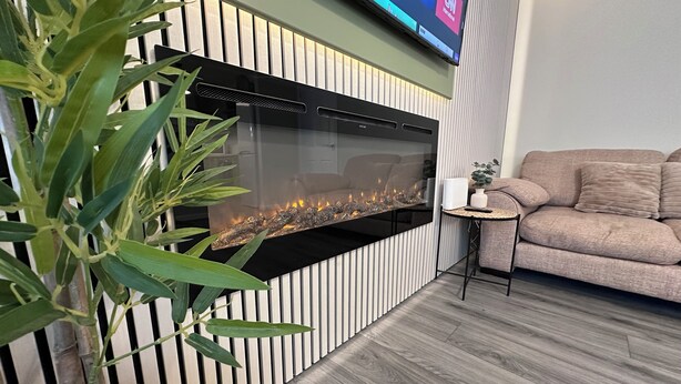 A modern living room with a built-in fireplace, a comfortable sofa, and a television mounted on the wall. - Modern Spacious 2-Bed Apartment • Sleeps 4 • Near City Centre free parking (Manchester)
