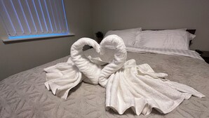 A bed with a white textured bedspread and two towels arranged in a heart shape. - Modern Spacious 2-Bed Apartment • Sleeps 4 • Near City Centre free parking (Manchester)