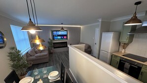A modern kitchen with a dining area, a flat-screen TV, and a sofa in the living room. - Modern Spacious 2-Bed Apartment • Sleeps 4 • Near City Centre free parking (Manchester)
