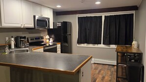 A modern kitchen with white cabinets, a black refrigerator, a microwave, and a coffee maker.