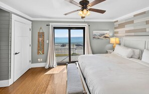 A bedroom with a bed, a ceiling fan, a view of the ocean through a sliding door, and a balcony with a railing. - Costa Vista Townhouse #13 (Miramar Beach)