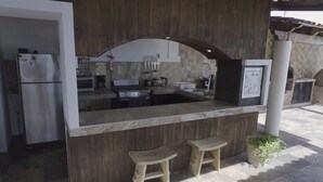 A kitchen with a marble countertop, wooden stools, a refrigerator, and a stove. - The Colony La Ventana (La Ventana)