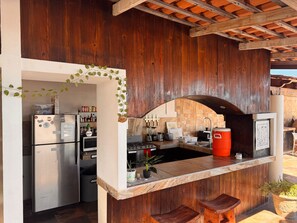 A kitchen with a refrigerator, stove, and sink, featuring wooden walls and a tiled backsplash. - The Colony La Ventana (La Ventana)