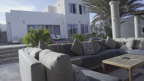 A modern outdoor seating area with a sofa, cushions, and a wooden table. - The Colony La Ventana (La Ventana)