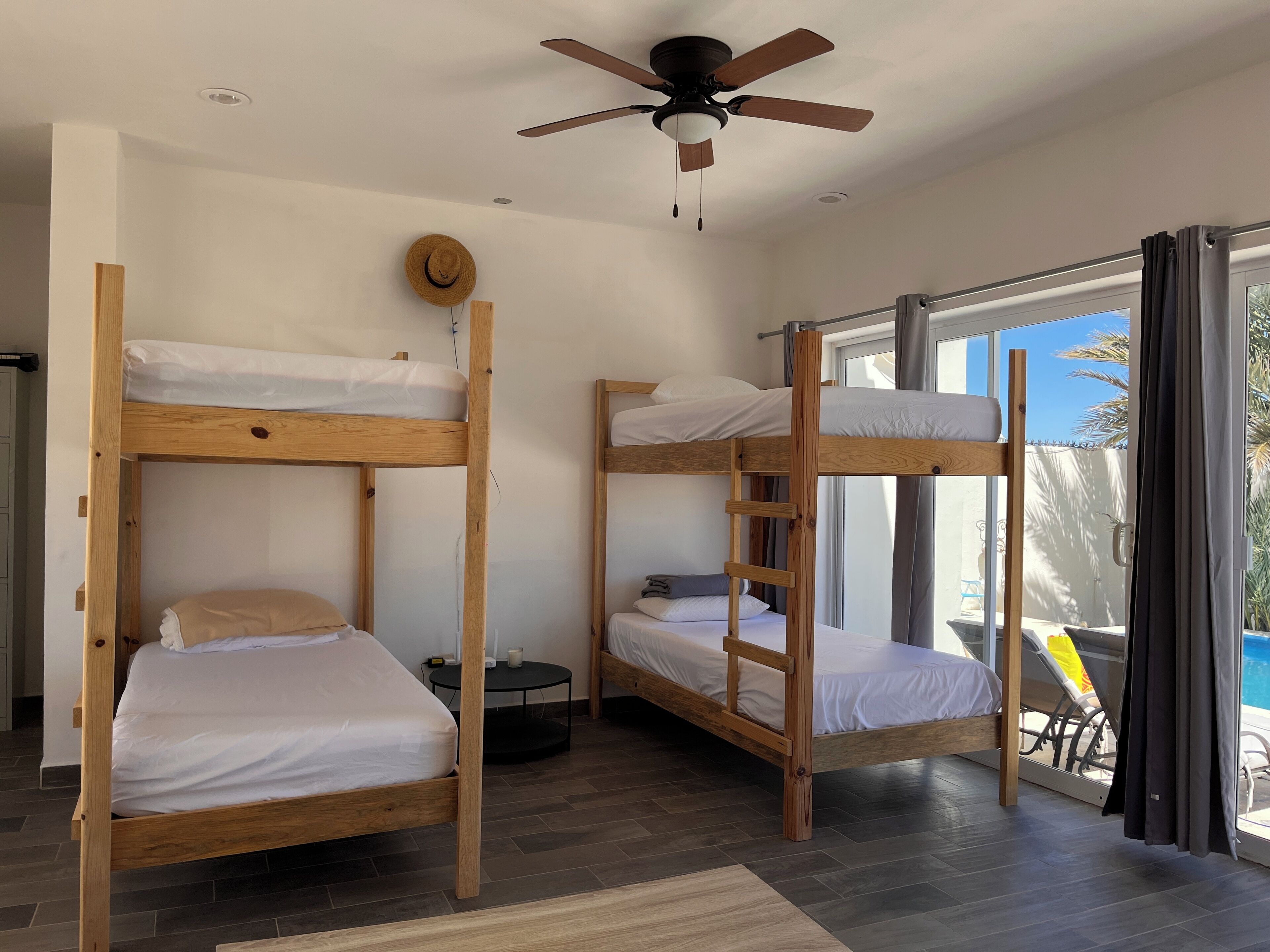 Una habitación con dos literas, un ventilador de techo, una mesa redonda y vistas al exterior.