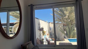 A room with a large window, a round mirror, a sofa, and a small table. - The Colony La Ventana (La Ventana)