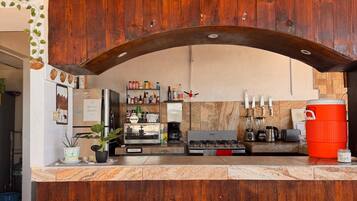 A rustic kitchen with wooden cabinets, a marble countertop, and a red cooler.