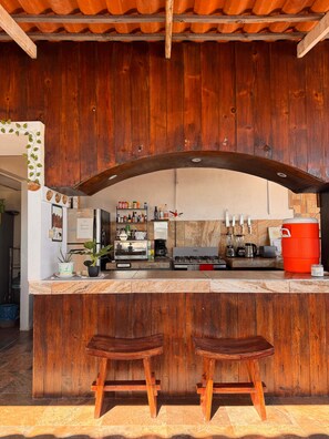 A rustic kitchen with wooden cabinets, a marble countertop, and a red cooler. - The Colony La Ventana (La Ventana)