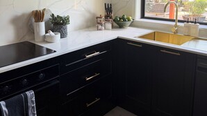 A kitchen with dark cabinets, a white countertop, and a window with a view of the outdoors.
