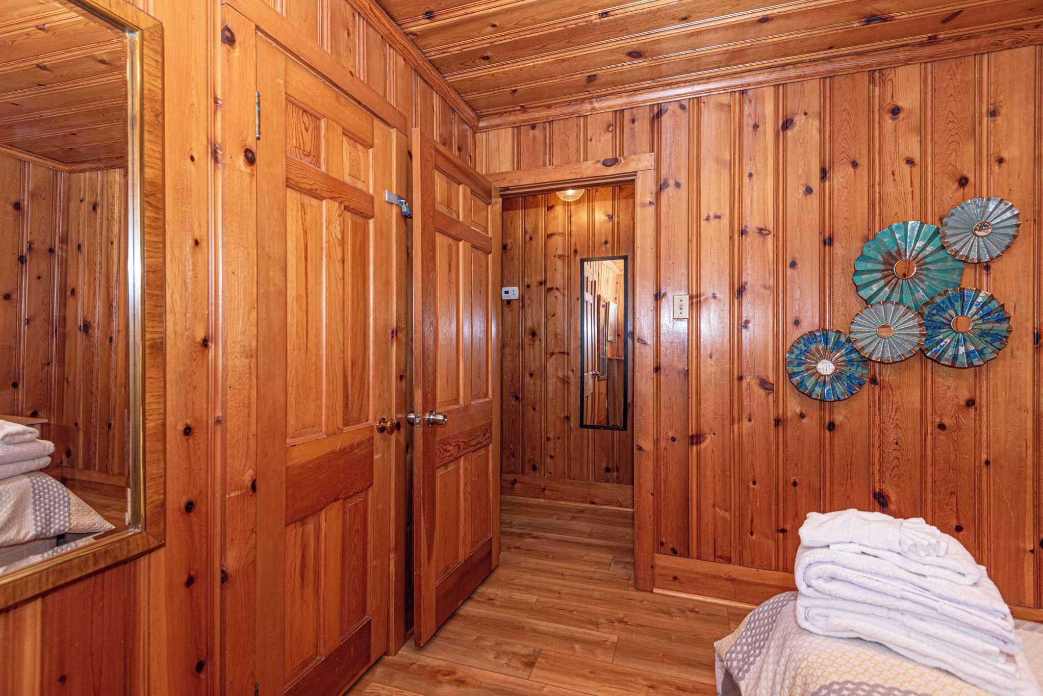 Een kamer met houten lambrisering, een spiegel, een deur en een ventilator aan de muur.