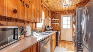 A wooden cabin kitchen with a stainless steel refrigerator, a microwave, and a dishwasher. - Spacious Group Retreat Steps to Beach (Ocean City)
